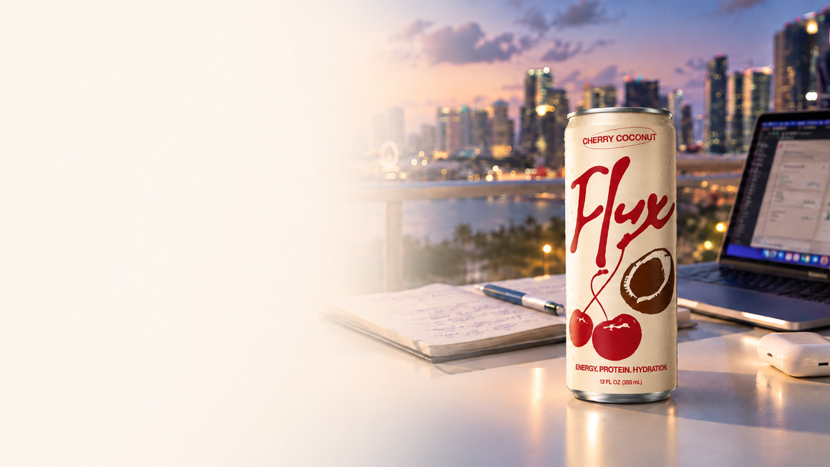Flux Cherry Coconut, Mango Pineapple and Mixed Berry cans with fresh fruit on a rock above a tropical ocean sunset